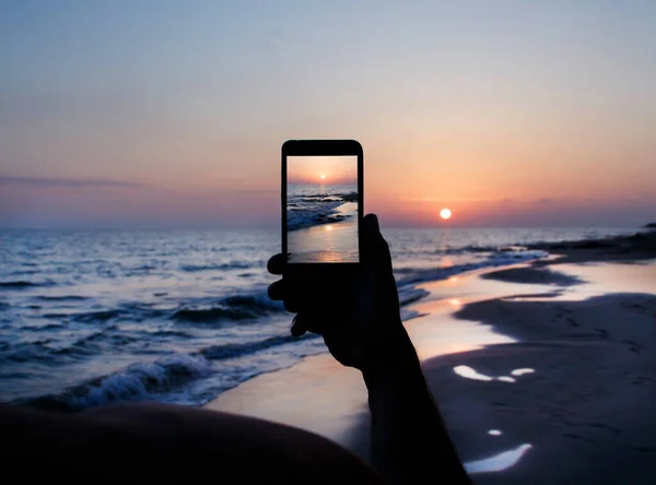男は携帯電話で夕日の写真を撮る — ストック写真