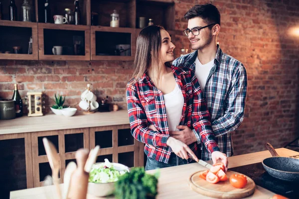 丈夫拥抱妻子 而妻子则在厨房里用碗煮新鲜蔬菜沙拉 膳食食品准备 夫妻准备浪漫的晚餐 健康的生活方式 — 图库照片