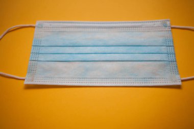 Sarı arkaplanda tek kullanımlık yüz maskesi