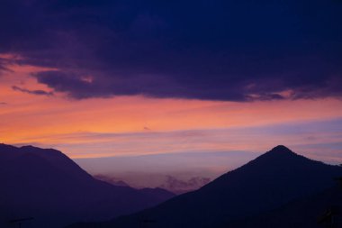 Dağların üzerinden gün batımının kızıl gökyüzü