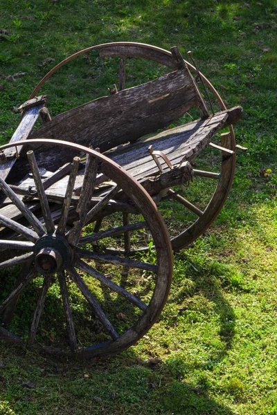 Güneşin aydınlattığı yeşil çimlerin üzerinde terk edilmiş eski ahşap bir araba.
