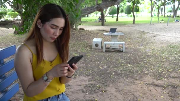 Νεαρή Ασιάτισσα Που Χρησιμοποιεί Smartphone Ενώ Κάθεται Στον Πάγκο Στο — Αρχείο Βίντεο