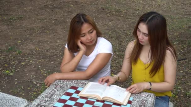 Duas Amigas Asiáticas Lendo Livro Parque Durante Dia — Vídeo de Stock