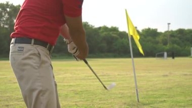 Erkek golfçü çimenli alanda golf oynuyor