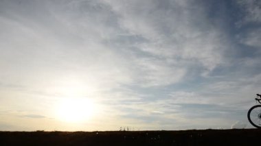 Gün batımında bisiklete binen insan silueti