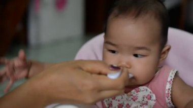 Anne tatlı Asyalı bebeği besliyor. 