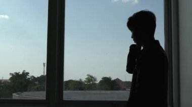 Ofiste akıllı telefon kullanan Asyalı iş adamının silueti 