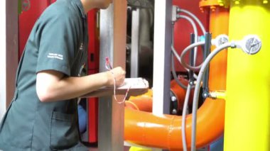 Kazan dairesinde çalışan Asyalı mühendis, ısıtma sistemi ekipmanlarının teknik verilerini kontrol ediyor.