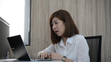 Ofiste oturan Asyalı iş kadını üzgün.