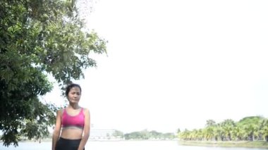 Genç Asyalı kadın gündüz vakti parkta egzersiz yapıyor. 