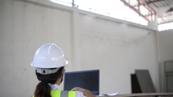 ビジネスの新しい場所である格納庫を確認しながらラップトップで入力する女性エンジニア — ストック動画