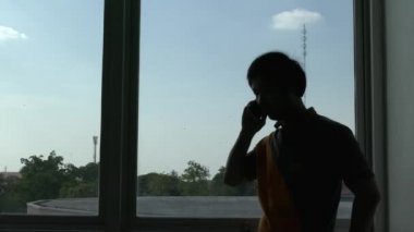 Pencere arkasında telefonla konuşan bir adamın silueti 