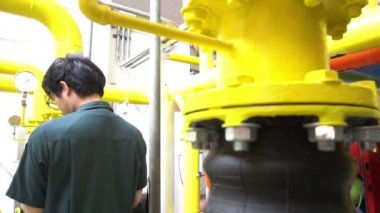 Kazan dairesinde çalışan Asyalı mühendis, ısıtma sistemi ekipmanlarının teknik verilerini kontrol ediyor.