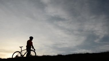 Gün batımında bisiklete binen insan silueti