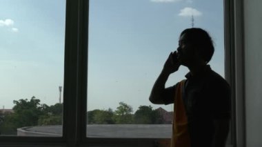 Ofiste akıllı telefon kullanan Asyalı iş adamının silueti 