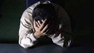 Erkek mahkum karakolda sorgu odasında oturuyor.