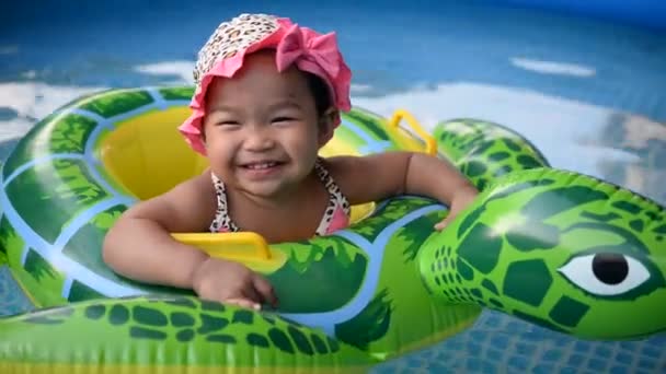 在游泳池里 戴着帽子的可爱的亚洲小女孩在管子里漂浮着 — 图库视频影像