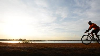 Gün batımında bisiklete binen insan silueti