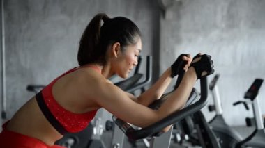 Spor salonunda antrenman yapan Asyalı sporcu kadın, egzersiz videosu.