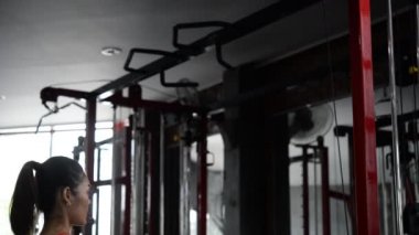Spor salonunda antrenman yapan Asyalı sporcu kadın, egzersiz videosu.