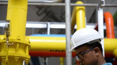 Kazan dairesinde çalışan Asyalı mühendis, ısıtma sistemi ekipmanlarının teknik verilerini kontrol ediyor.