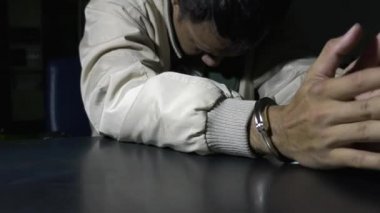 Erkek mahkum karakolda sorgu odasında oturuyor.