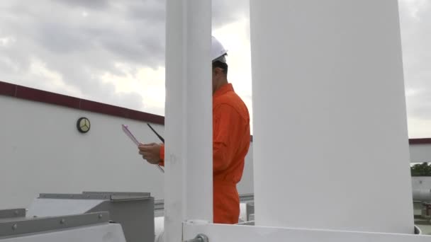 男工程师检查员 带着剪贴板检查设备在工厂屋顶上 用收音机说话 — 图库视频影像