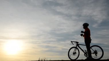 Gün batımında bisiklete binen insan silueti