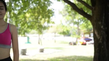 Genç Asyalı kadın gündüz vakti parkta egzersiz yapıyor. 