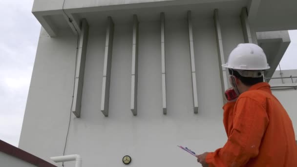 男工程师检查员 带着剪贴板检查设备在工厂屋顶上 用收音机说话 — 图库视频影像
