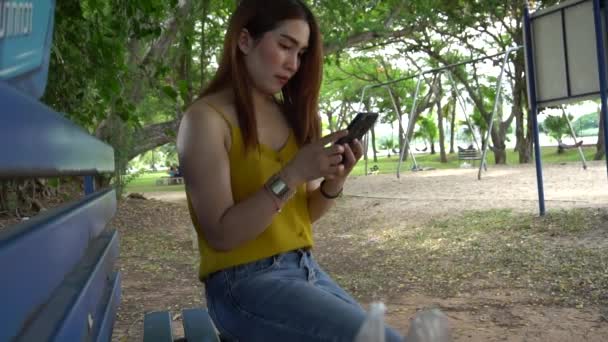 벤치에 스마트폰을 사용하는 아시아의 — 비디오
