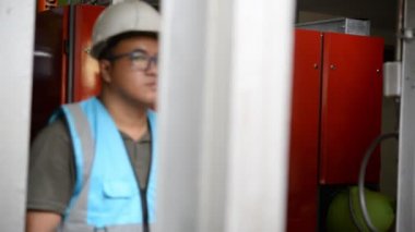 Kazan dairesinde çalışan Asyalı mühendis, ısıtma sistemi ekipmanlarının teknik verilerini kontrol ediyor.