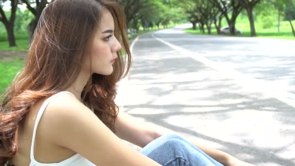 昼間道路脇に座っている若い美しいアジア系の悲しい女性 — ストック動画