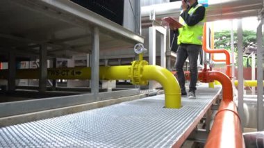Kazan dairesinde çalışan Asyalı mühendis, ısıtma sistemi ekipmanlarının teknik verilerini kontrol ediyor.