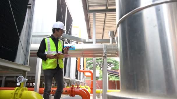 ボイラー室で働くアジアのエンジニア 暖房システム機器のメンテナンスチェック技術データ — ストック動画