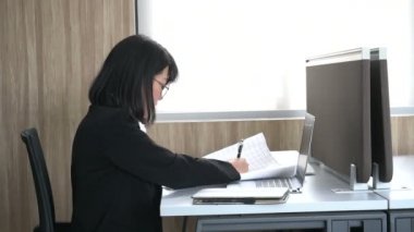 Ofiste çalışırken dizüstü bilgisayarda yazan Asyalı iş kadını.