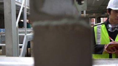 Kazan dairesinde çalışan Asyalı mühendis, ısıtma sistemi ekipmanlarının teknik verilerini kontrol ediyor.