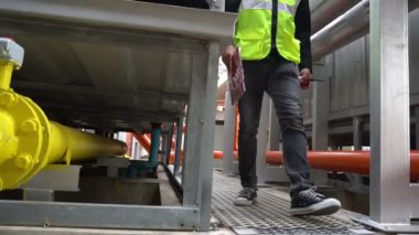 Kazan dairesinde çalışan Asyalı mühendis, ısıtma sistemi ekipmanlarının teknik verilerini kontrol ediyor.