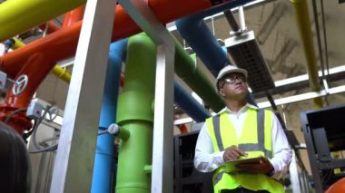 Büyük bir fabrikanın atık su yönetim sisteminde Asya Bakım Mühendisi, Tayland 'daki ısıtma sistemi ekipmanlarının teknik verilerini kontrol ediyor.