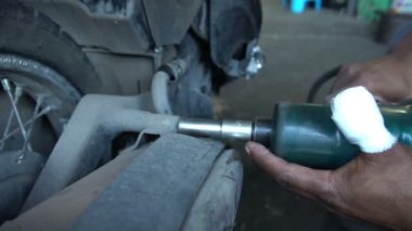 Motosiklet tamir eden adama yaklaş. 