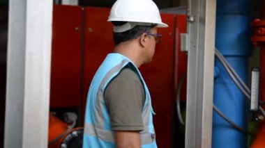 Kazan dairesinde çalışan Asyalı mühendis, ısıtma sistemi ekipmanlarının teknik verilerini kontrol ediyor.