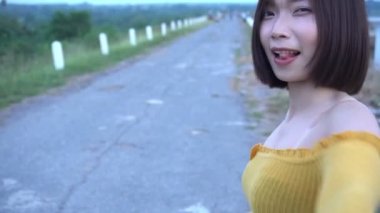 Sarı elbiseli güzel Asyalı kadın dışarıda poz veriyor. 