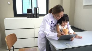 Asyalı doktor steteskop kullanarak güzel bir kızın kalbini ve nefesini kontrol ediyor.