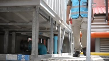Kazan dairesinde çalışan Asyalı mühendis, ısıtma sistemi ekipmanlarının teknik verilerini kontrol ediyor.