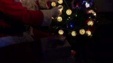 Noel Baba 'nın Noel ağacını çelenkle süslemesi, mutlu bayramlar.