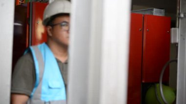 Kazan dairesinde çalışan Asyalı mühendis, ısıtma sistemi ekipmanlarının teknik verilerini kontrol ediyor.