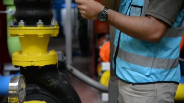 Kazan dairesinde çalışan Asyalı mühendis, ısıtma sistemi ekipmanlarının teknik verilerini kontrol ediyor.