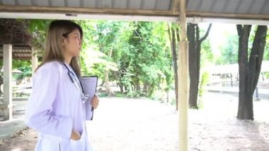 Dışarıda duran steteskoplu genç bayan doktor manzarası. 