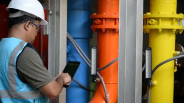Kazan dairesinde çalışan Asyalı mühendis, ısıtma sistemi ekipmanlarının teknik verilerini kontrol ediyor.