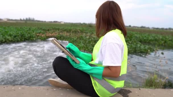 女性生態学者が水洗い場近くで働いています — ストック動画